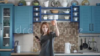 女人红发打开智能手机音乐在厨房里劲舞